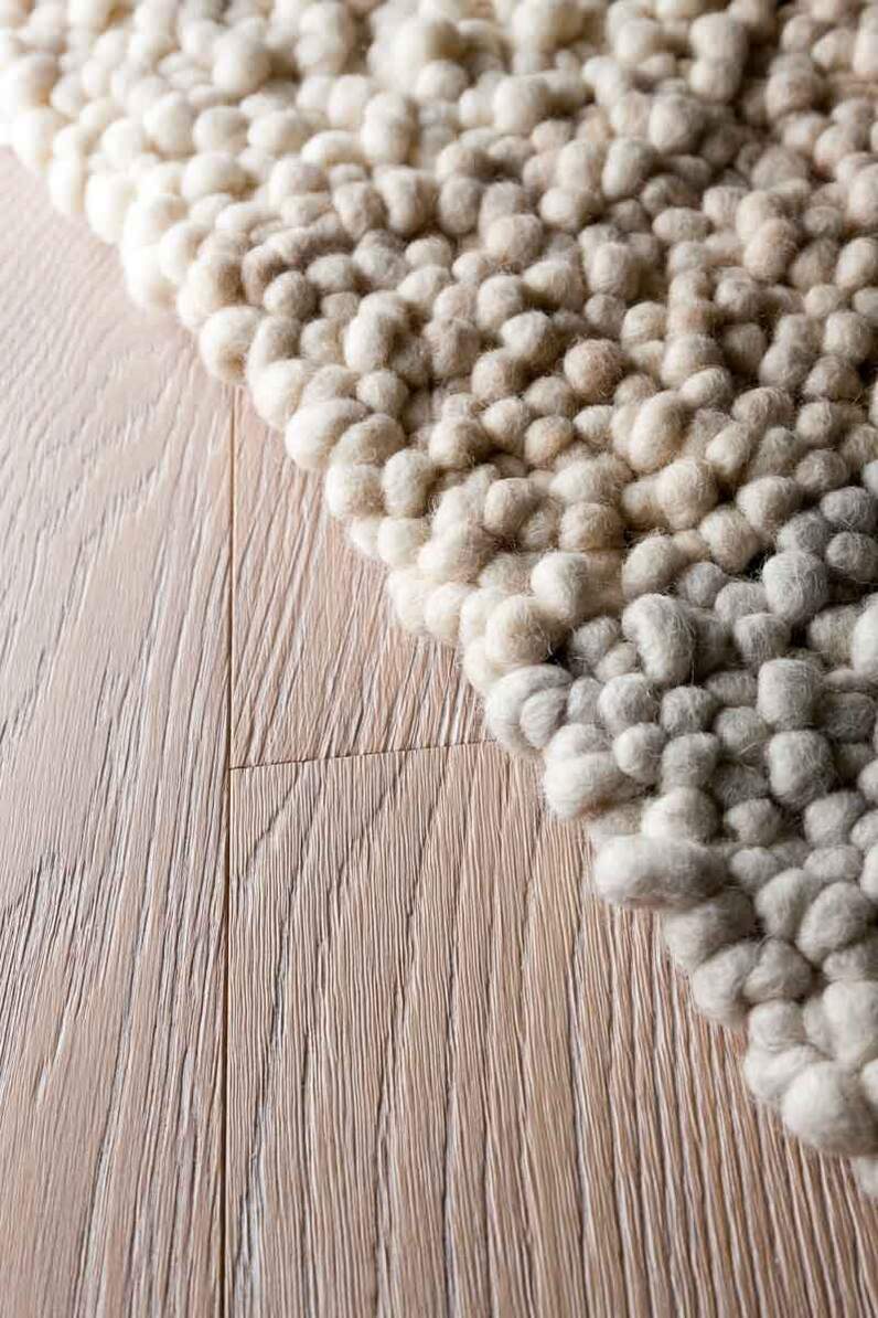 Nahaufnahme einer Teppichkante auf einem Holzboden